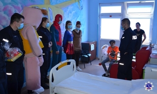 Przedstawiciele szkolnego samorządu stoją przy siedzącym chłopcu – pacjencie pilskiego szpitala. Widać spidermana i różowego stwora